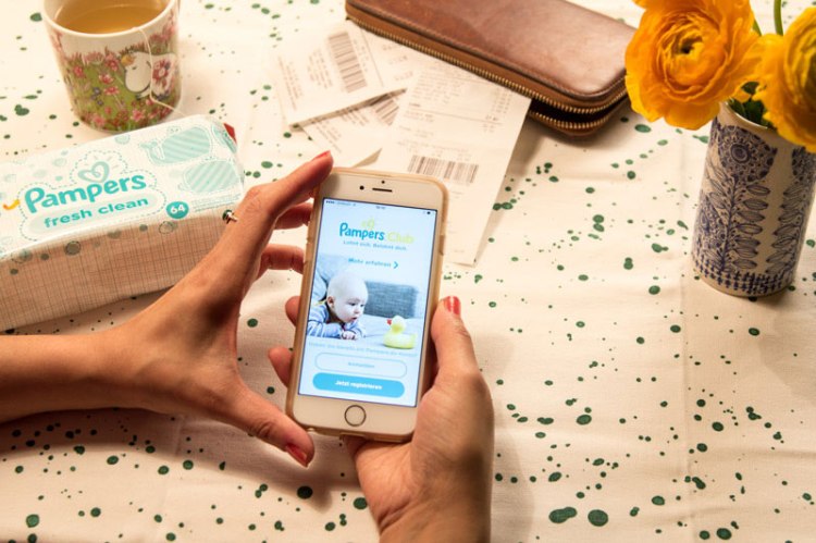 Frau mit Handy testet die neue Pampers-Club-App