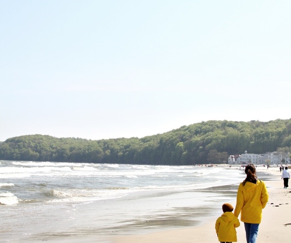 Mutter und Kind mit gelben Regenjacken von Petit Bateau am Strand von Binz auf Rügen